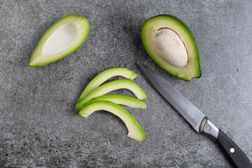 green avocado lie on an artificial stone board. diet food. green vegetable.