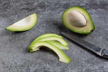 green avocado lie on an artificial stone board. diet food. green vegetable.
