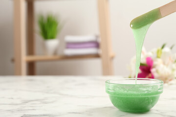 Spatula with wax on white marble table. Space for text