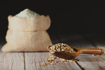 Dry paddy rice on wooden scoop with rustic wood table background. Dark tone