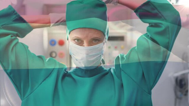 Animation of flag of netherlands waving over female surgeon in operating theatre