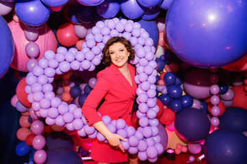 Fototapeta na wymiar Fashion portrait of young stylish woman surrounded by many pink and purple balloons