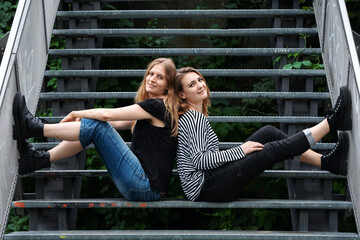 Portrait of two beautiful young women sitting outside on stairs