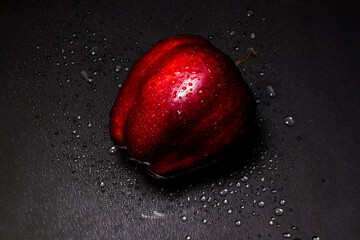fresh red apple with droplets of water against black background