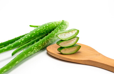 Sliced ​​fresh green aloe leaves in a wooden spoon isolated on white background. Skincare concept health and beauty spa

