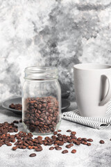 Jar of coffee beans with a grey mug at the back