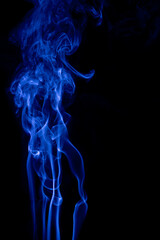 The movement of blue smoke faces a fierce fierce black background on abstract things on a black background.