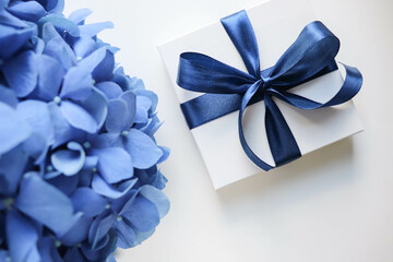 romantic composition of blue flowers on white background and gift box with blue bow