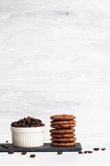 A small bowl of coffee beans with a stack of cookies at the side