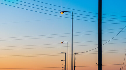 Row of street lights and wires in the colorful sunset sky background