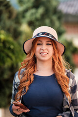 A red-haired girl with a hat in the park is holding phone