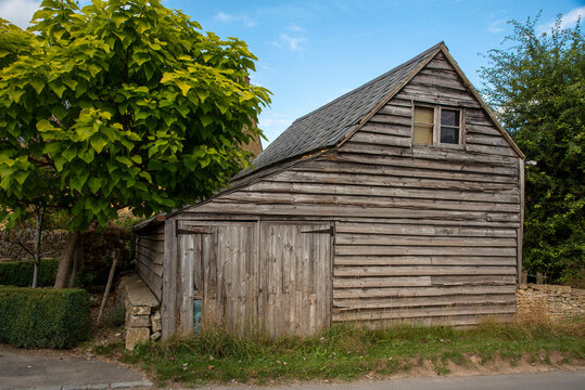 Guiting Power, Gloucestershire, England, UK. 2021.  An old wooden barn with small garage doors in the rural Cotswolds village of Guiting Power.