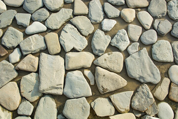 background of stones of approximately the same shape on wet sand on the ocean shore
