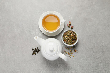 Obraz na płótnie Canvas Fresh brewed tea and dry leaves on light grey background, flat lay