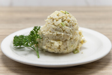 Generous scoop of potato salad served on a plate garnished with parsley