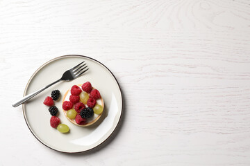Naklejka na ściany i meble Delicious tartlet with berries on white wooden table, top view. Space for text