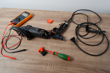 Power tool repair. Angle grinder disassembled for repair on the table. Screwdriver, multimeter.