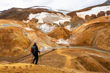 Woman with a backpack hiking in Hveradali geothermal area in Kerlingarfjoll mountain. Iceland Highlands