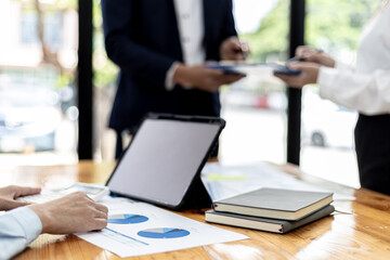 A female employee looks at the financial information sheet, she is attending a meeting with the management team to finalize the company's financial reports. Startup company meeting concept.