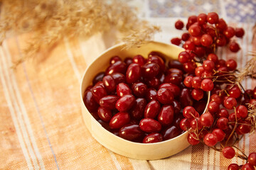 Organic autumn berries of viburnum and dogwood in wooden bowl in cozy home interior. Healthy food for tea, compote and jam concept. Top view background, copy space. High quality photo