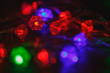 The Christmas garland glows in the dark with different colors. Horizontal photo with bokeh. Decor for New Year.