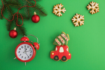 Christmas gingerbreads in the shape of car, snowflake, fir and red alarm clock on the green background. Top view. Copy space.