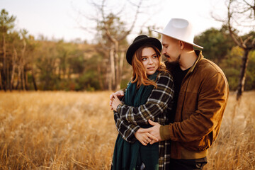 Young couple walking in the autumn park. Enjoying time together. Love story. Autumn style.