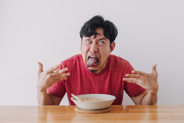 Funny face of Asian man eat very hot and spicy instant noodle.