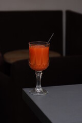 tomato juice in a transparent glass on a gray table