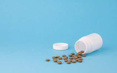 A bottle of brown pills, on a blue background with copy spase