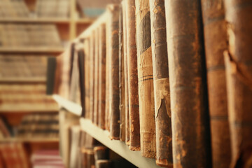 Different old books on shelf in library, closeup