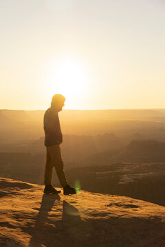 man hiking at sunrise in canyonlands national park in the summer in moab uath