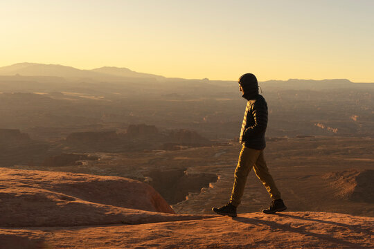 man hiking at sunrise in canyonlands national park in the summer in moab uath
