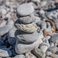 Zen balance stones, smooth rocks pyramid stacked on pebble beach background.