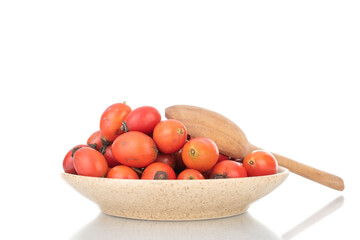 Several bright red ripe wild rose berries in a ceramic dish, close-up, isolated on white.
