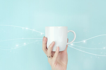 Cropped view of female hand with white coffee cup and digital wave on blue background.