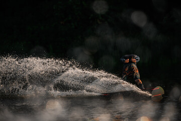 Man wakeboarder having fun and make tricks riding on the board at splashing river wave.