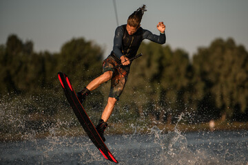 male wakeboarder having fun and jump on the board at splashing river wave