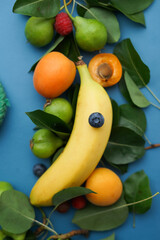 one ripe beautiful banana on a background of fruits and berries on a blue background