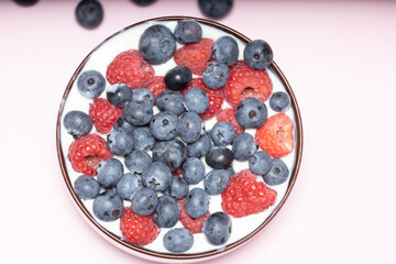 Raspberries and blueberries in a cup with yogurt.