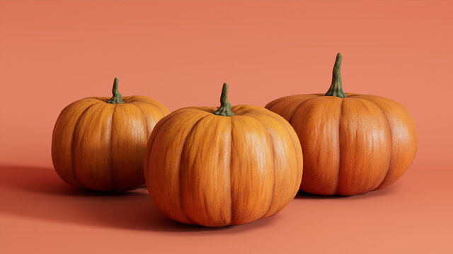 Three Pumpkins on a Salmon Pink colored background. Autumn themed Image.