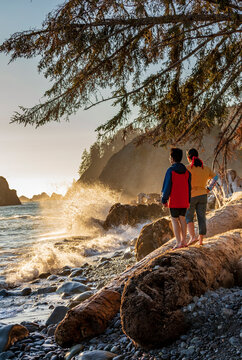 mother and son watching the golden  sunset in Rialto Beach as powerful waves hit the shore