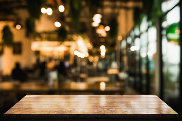 Empty wooden table top with lights bokeh on blur restaurant background.