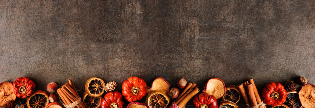 Autumn baking spices and ingredients. Bottom border on a dark stone banner background with copy space. Top down view.