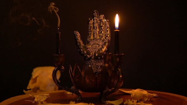 Fortune teller hand or palmistry on the witch table with animal bones. Palmistry with black palm and candles in the candelabra. Magic alchemy spirituality symbol. Palm reading in mystic, occult room.