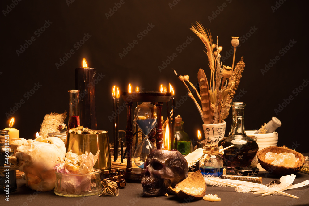 Wall mural Selective focus on human skull candle. Occult and esoteric witch doctor still life. Halloween with magic objects. Black candle, crystal stones, teeth potions bottles on witch table. Mystic witchery.