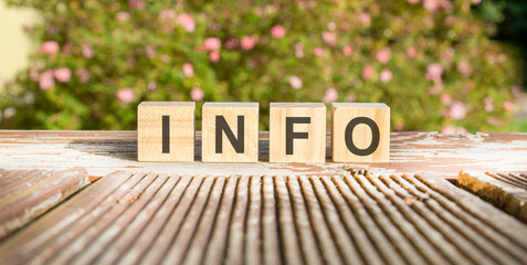 text of the word INFO on wooden cubes. flowers in the background - obrazy, fototapety, plakaty