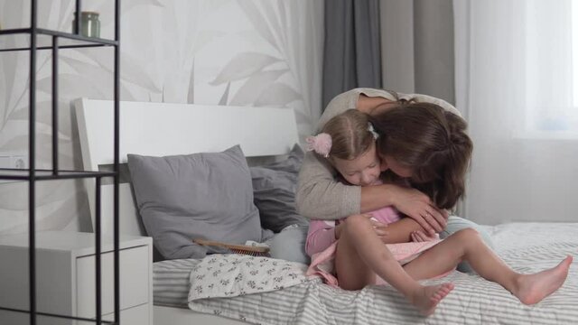 Mom hugs and kisses the little baby at home before taking the baby to kindergarten.