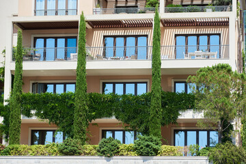 Facade of a building with climbing plants and cypresses