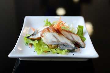Fresh salad with fish and carrot on black background.